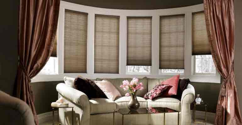 Vertical honeycomb shades in living room bow window.